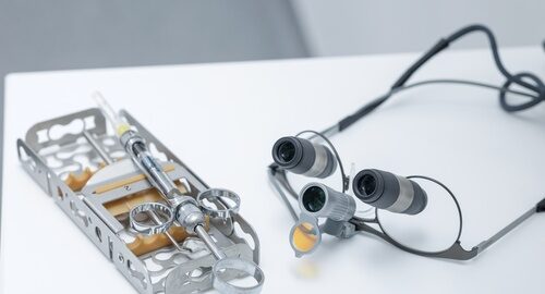 Closeup,Of,Dental,Loupes,,Surgical,Syringe,And,Metal,Tray,Instruments Closeup,Of,Dental,Loupes,,Surgical,Syringe,And,Metal,Tray,Instruments